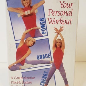 Puede incluir: Una cinta de video VHS con Heather Locklear, una instructora de fitness, demostrando una rutina de entrenamiento. La portada presenta un fondo azul con el título "Your Personal Workout" e imágenes de Heather Locklear realizando diferentes ejercicios. Las palabras "Power", "Grace" y "Energy" están escritas en la portada.
