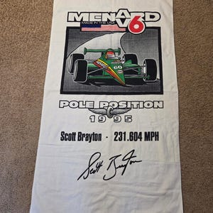 Puede incluir: Toalla de carreras blanca con un coche de carreras verde y rojo, el texto "MENARD 6" y "POLE POSITION 1995". También presenta "Scott Brayton - 231.604 MPH" y una firma.