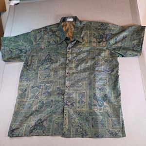 以下が含まれることがあります： 緑と青の模様が施された半袖ボタンダウンシャツ。 シャツは襟付きで、シルクのような素材で作られています。 パターンは幾何学模様と花柄を特徴としています。