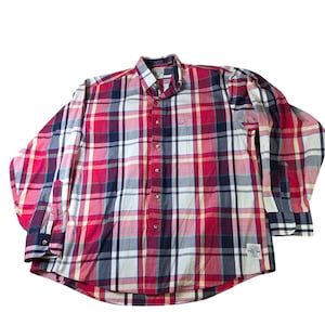 Puede incluir: Una camisa abotonada de manga larga con un patrón de cuadros clásico. La camisa presenta una combinación de colores rojo, blanco y azul marino. Tiene cuello abotonado, bolsillo en el pecho y puños abotonados. La camisa está hecha de tela ligera.