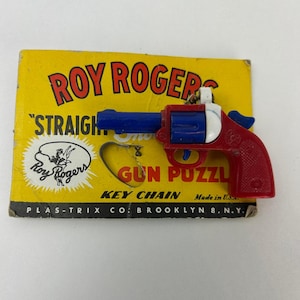 May include: A vintage Roy Rogers "Gun Puzzle" key chain. The toy gun is red, white, and blue, with the text "Roy Rogers" in red on a yellow background. The key chain is made in the USA.