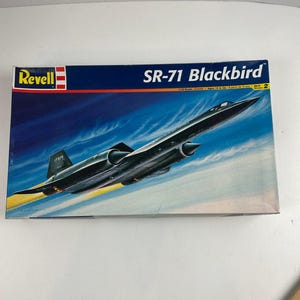 Puede incluir: Caja de modelo de Revell con el avión SR-71 Blackbird. La caja tiene un fondo azul con el avión en vuelo. El texto "SR-71 Blackbird" está en blanco, y el logotipo de Revell está en la esquina superior izquierda.