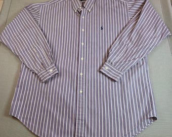 May include: A long-sleeved button-down shirt with vertical stripes in shades of purple and white. The shirt features a button-down collar, a small embroidered logo on the chest, and buttoned cuffs. The shirt is made of a lightweight fabric.