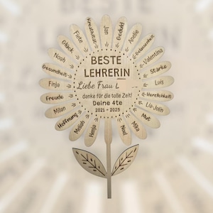 Könnte beinhalten: Eine holzgeschnitzte Blume mit den Worten "BESTE LEHRERIN" und "Liebe Frau L" in der Mitte. Die Blütenblätter sind mit Namen und Phrasen beschriftet. Der Stiel hat Blätter, und der Text "danke für die tolle Zeit! Deine 4te 2021-2025" ist ebenfalls vorhanden.