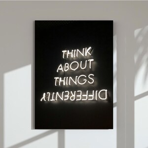 Könnte beinhalten: Schwarzes und weißes Neon-Schild mit dem Text "Think about things differently".
