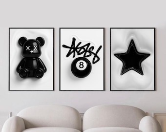 May include: Three framed art prints featuring a black bear figure, a black and white eight ball, and a black star. The prints have a black frame and are set against a white background with a swirling effect. The word "ABBS" is written above the eight ball.