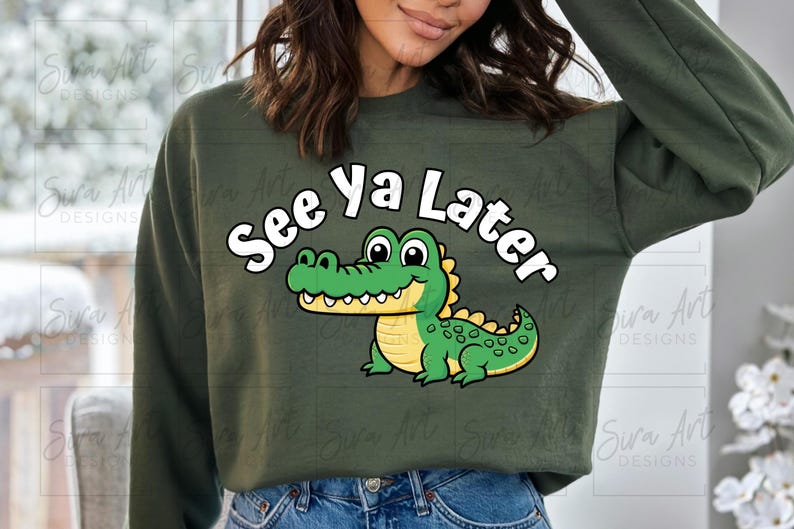 K&ouml;nnte beinhalten: Ein gr&uuml;ner Pullover mit einem Karikatur-Alligator und dem Text "See Ya Later" in Wei&szlig;.