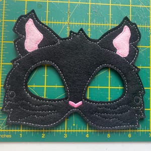 May include: Black felt cat mask with pink felt ears and eye holes. The mask is approximately 6 inches wide.