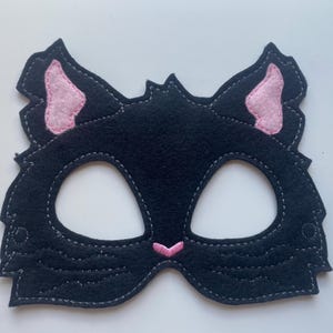 May include: Black felt cat mask with pink felt ears and a pink felt nose. The mask has eye holes for seeing.