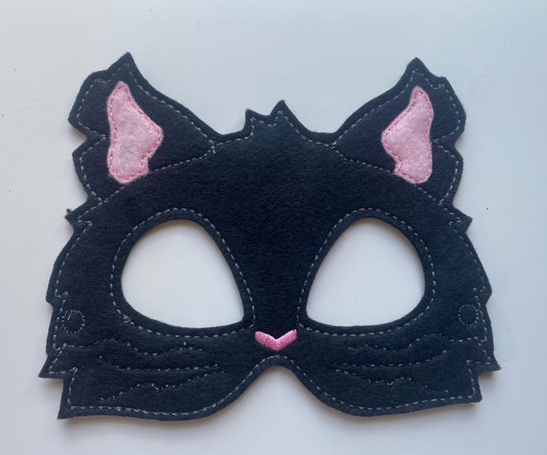 May include: Black felt cat mask with pink felt ears and a pink felt nose. The mask has eye holes for seeing.