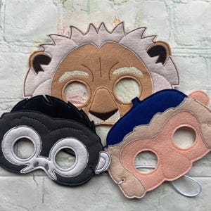 May include: Three felt animal masks for kids. A lion mask with a brown face and a white mane, a monkey mask with a black face and white eyes, and a sheep mask with a pink face and blue hat.
