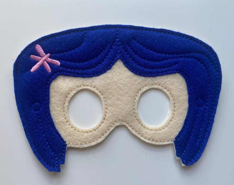 May include: Blue felt eye mask with a pink flower detail. The mask is shaped like a girl's face with a blue wig.