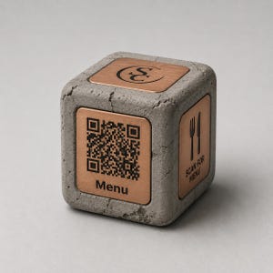 May include: A grey concrete cube with bronze metal plates. One plate displays a QR code and the word "Menu". Another plate has a knife and fork icon with the text "Scan for Menu". The top plate has a stylized logo.