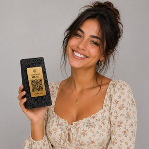 Könnte beinhalten: Eine lächelnde Frau hält ein schwarzes, rechteckiges Objekt mit einem goldenen Etikett. Das Etikett zeigt einen QR-Code und den Text "SCAN FOR MENU" und "THANK YOU". Sie trägt ein Oberteil mit Blumenmuster.