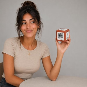 Könnte beinhalten: Ein kleiner, rotbrauner Würfel mit QR-Codes und dem Wort "Menü" aufgedruckt. Der Würfel zeigt auch das Instagram-Logo. Der Würfel wird vor einer Person hochgehalten.