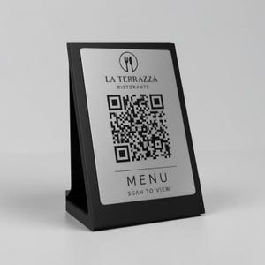 Könnte beinhalten: Ein schwarzer Tisch-Menühalter mit einer silbernen Platte. Die Platte zeigt den Text "LA TERRAZZA RISTORANTE", einen QR-Code und die Worte "MENU SCAN TO VIEW". Der Halter hat ein schlichtes, modernes Design.