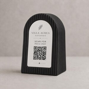 Pode incluir: Suporte de código QR preto, arqueado, com textura canelada vertical. O rótulo branco diz "VILLA AUREA RISTORANTE" e "SCANEAR PARA MENU E ENCOMENDAR" com um código QR e um pequeno design floral.