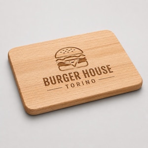Pode incluir: Uma tábua de servir retangular de madeira castanho-clara com cantos arredondados. O centro apresenta um gráfico gravado a laser de um hambúrguer acima do texto BURGER HOUSE TORINO, sublinhado por uma linha horizontal.