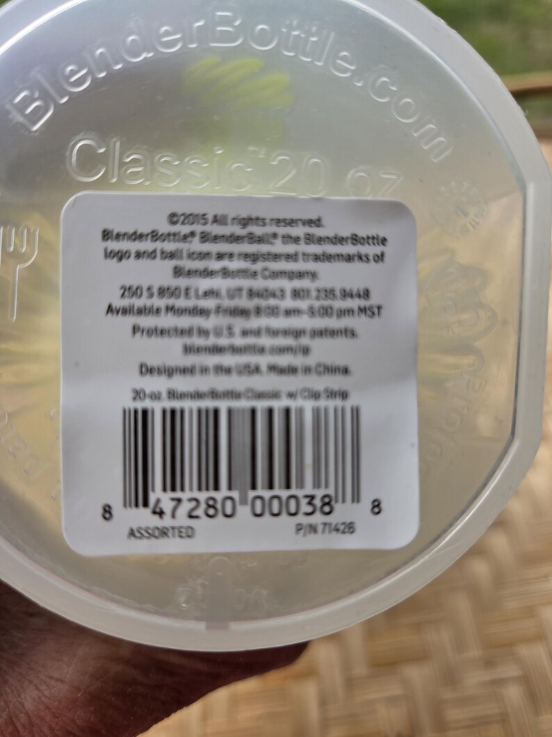 May include: A clear BlenderBottle Classic with a 591 ml capacity. The bottle has a white label with black text, including the BlenderBottle logo and product information. Designed in the USA, made in China.
