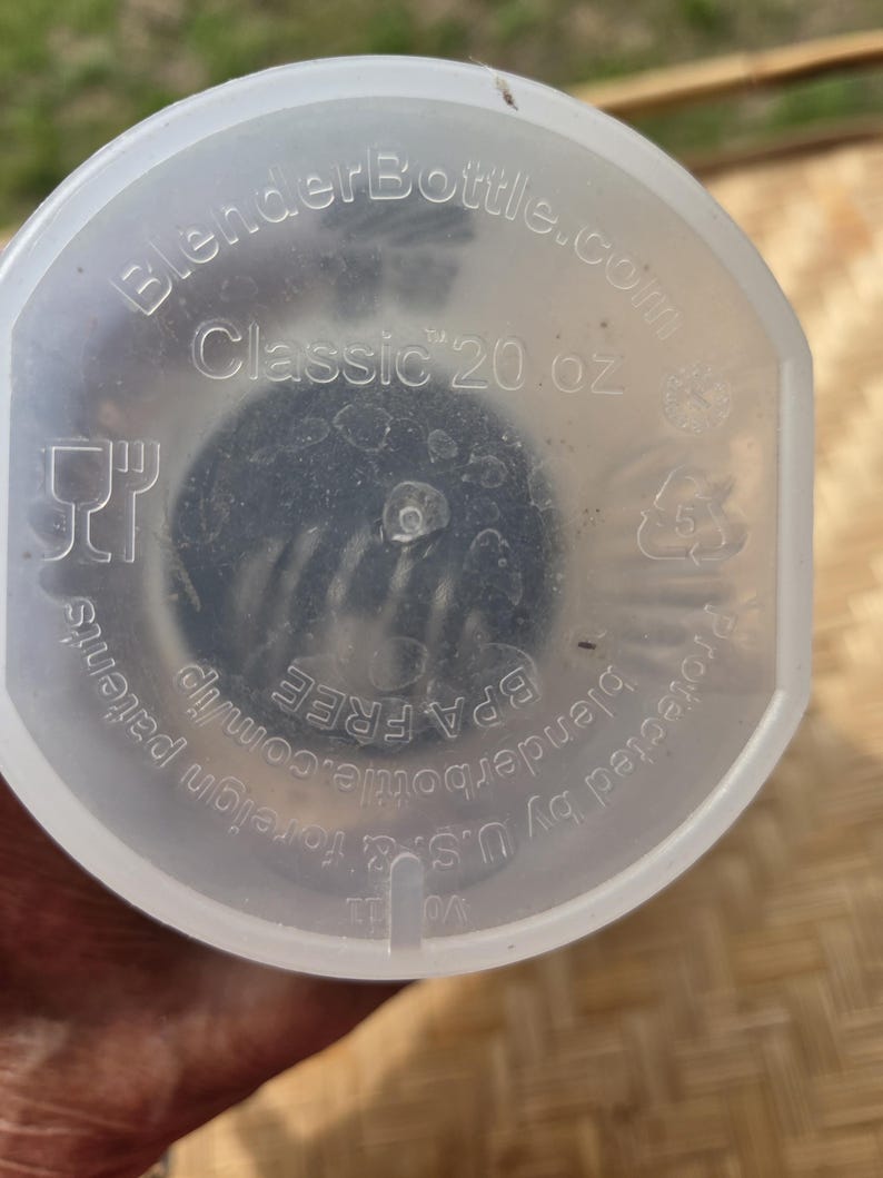 K&ouml;nnte beinhalten: Ein klarer BlenderBottle-Deckel mit dem Text "Classic 20 oz." und "BlenderBottle.com" aufgedruckt. Der Deckel ist BPA-frei und durch US-amerikanische und ausl&auml;ndische Patente gesch&uuml;tzt.