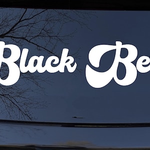 May include: White vinyl decal with the text "Black Betty" in a retro font style. The decal is on a dark blue car.