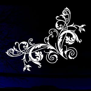 May include: A white vinyl decal featuring an intricate corner flourish design with swirling filigree, ornate leaf patterns, and delicate scrollwork. The graphic is composed of symmetrical curves and pointed foliage elements arranged in a corner shape.