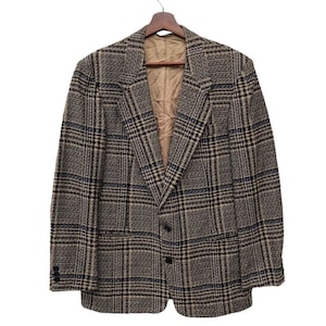 May include: A brown, black, and blue plaid blazer hanging on a wooden hanger. The blazer has a two-button closure and two front pockets. The interior lining is a tan colour.