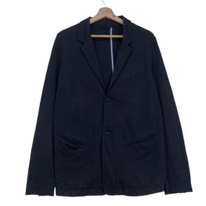 May include: A navy blue blazer with two front pockets and a two-button fastening. The jacket is suspended from a wooden hanger. The blazer features a notched lapel and a single vent at the rear.
