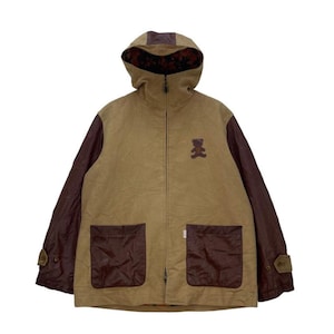 May include: A tan jacket with a hood and brown sleeves. The jacket features two front pockets and a small teddy bear patch on the chest. The hood lining has a floral pattern.