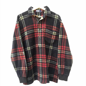 Puede incluir: Una camisa de manga larga a cuadros negros, rojos y blancos con cuello abotonado. La camisa tiene un bolsillo en el pecho y puños negros. El logotipo de Polo Ralph Lauren es visible en la etiqueta.