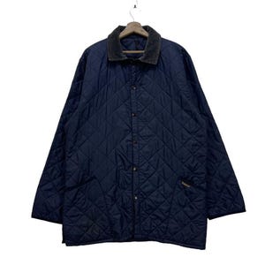 May include: A navy blue quilted jacket with a corduroy collar, hanging from a wooden hanger. The jacket has a diamond pattern, button closure, and two front pockets. The brand name is embroidered on the pocket.