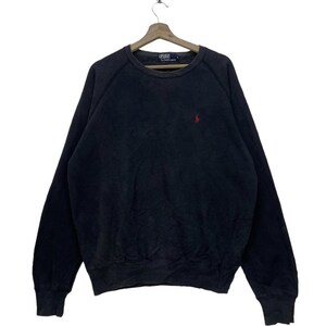 May include: A dark navy blue sweatshirt with a crew neck and long sleeves. The sweatshirt features a small red polo logo on the left chest. The garment is hanging on a wooden hanger.