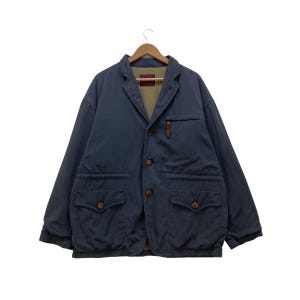 Puede incluir: Chaqueta azul marino de estilo blazer. Tiene solapas con muescas, tres botones y dos bolsillos delanteros grandes con cierre de botón. Hay un pequeño bolsillo en el pecho y un tirador de cremallera de cuero marrón.