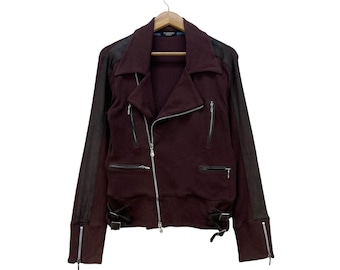 May include: A burgundy motorcycle jacket with black leather sleeves and accents. The jacket features a zipper closure, multiple zippered pockets, and adjustable cuffs with zippers. It hangs on a wooden hanger against a white background.