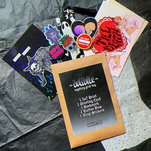 May include: A mystery grab bag with various items, including a 5x7 print, greeting card, bookmark, button pins, and vinyl stickers. The items feature gothic and alternative art, with a black and white color scheme. The bag is on a textured black surface.
