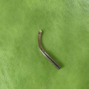 May include: A silver metal sewing machine foot with a curved shape and two holes.
