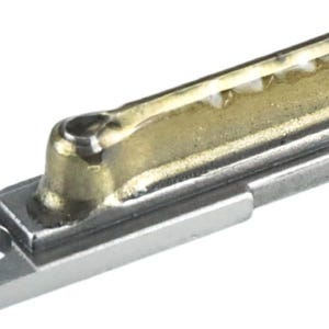 May include: A close-up of a silver and gold metal key blank. The key blank has a unique design with a small, round hole in the center.