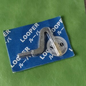 Puede incluir: Un looper de máquina de coser plateado con una punta dorada. El looper está empaquetado en una tarjeta azul con el texto "Looper" en blanco y caracteres japoneses. La tarjeta también tiene el texto "Hecho en Taiwán" y un logotipo con las letras "SCO".