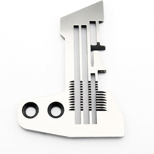 Può includere: Un piedino per macchina da cucire in argento con una serie di scanalature e una piccola leva. Il piedino ha due fori sul fondo.