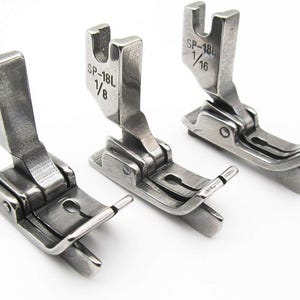 May include: Three silver sewing machine presser feet with the text "SP-18L 1/8" and "SP-18L 1/16" printed on them.