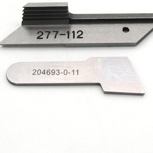 May include: Two metal tools with numbers printed on them. The top tool is a metal blade with a series of ridges on the top and the number "277-112" printed on the side. The bottom tool is a metal blade with the number "204693-0-11" printed on the side.