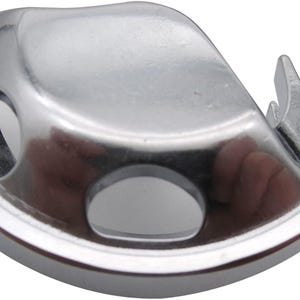 May include: A silver bobbin case for a sewing machine. The case has a smooth, rounded shape with a small opening on the side.