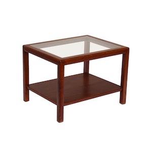 May include: A dark brown wooden end table with a glass top and a lower shelf. The table has a simple, mid-century modern design.