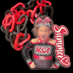 May include: A red and black chain necklace with a pendant featuring a cheerleader in a USA uniform. The pendant has the name "Summer" in red script with a heart. The cheerleader is wearing a red bow.