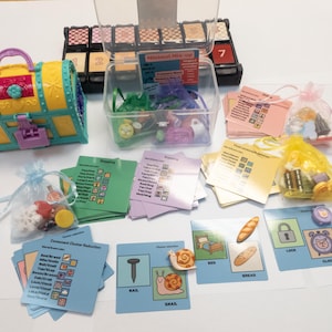 May include: A collection of educational toys and cards, including a toy chest, clear containers with small objects, and cards with words and images. The cards feature words like "nail," "snail," "bed," and "bread."