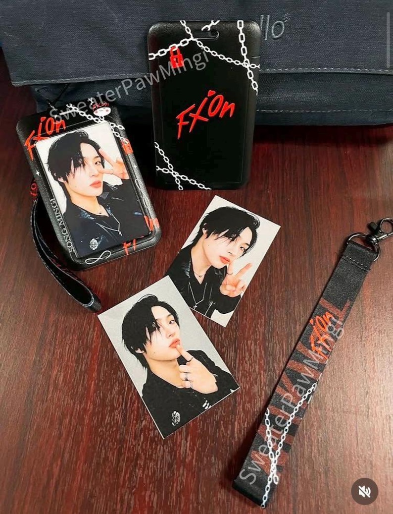 May include: A black plastic ID badge holder with a chain pattern and red text reading FXion, two rectangular photo cards featuring a person with black hair, and a black fabric lanyard with red and white chain graphics and the text SweaterPawMing.