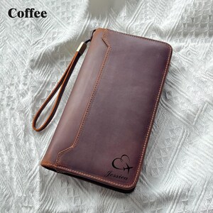 May include: A brown leather wallet with a wrist strap. The wallet has a stitched design and the name "Jessica" is printed on the front, along with a heart and airplane graphic. The word "Coffee" is in the top left corner.