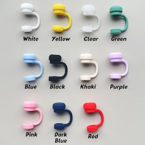 May include: A collection of colorful silicone straw covers in white, yellow, clear, green, blue, black, khaki, purple, pink, dark blue, and red. Each cover has a rounded top and a curved, U-shaped design with a small opening at the bottom. Text labels identify each color.
