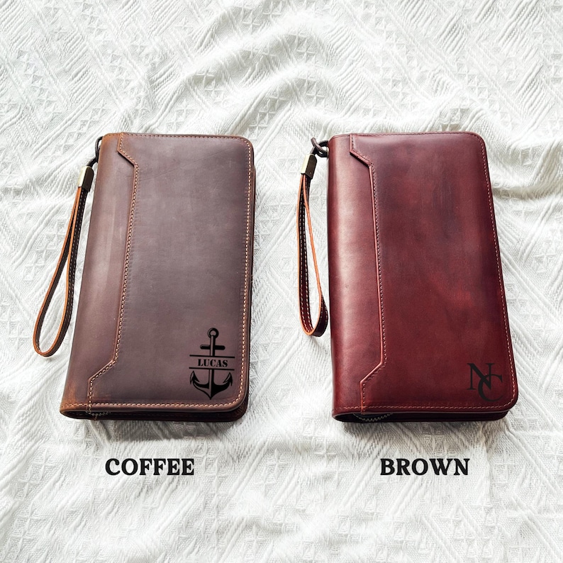 May include: Two leather wallets, one coffee-colored and one brown, with wrist straps. The coffee-colored wallet has an anchor design and the name "LUCAS". The brown wallet has the initials "N".