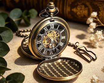 May include: An antique-style bronze pocket watch with an open face revealing a black dial, white Roman numerals, and a visible gold-toned mechanical movement. The watch features a hinged cover with a textured pattern and an attached metal chain.